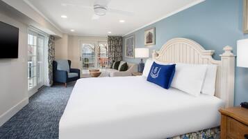 A hotel room with a large bed, a chair, a desk, and a television.