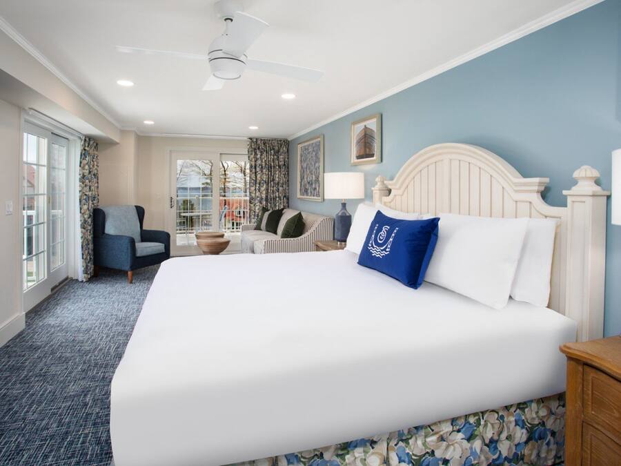 A hotel room with a large bed, a chair, a desk, and a television.