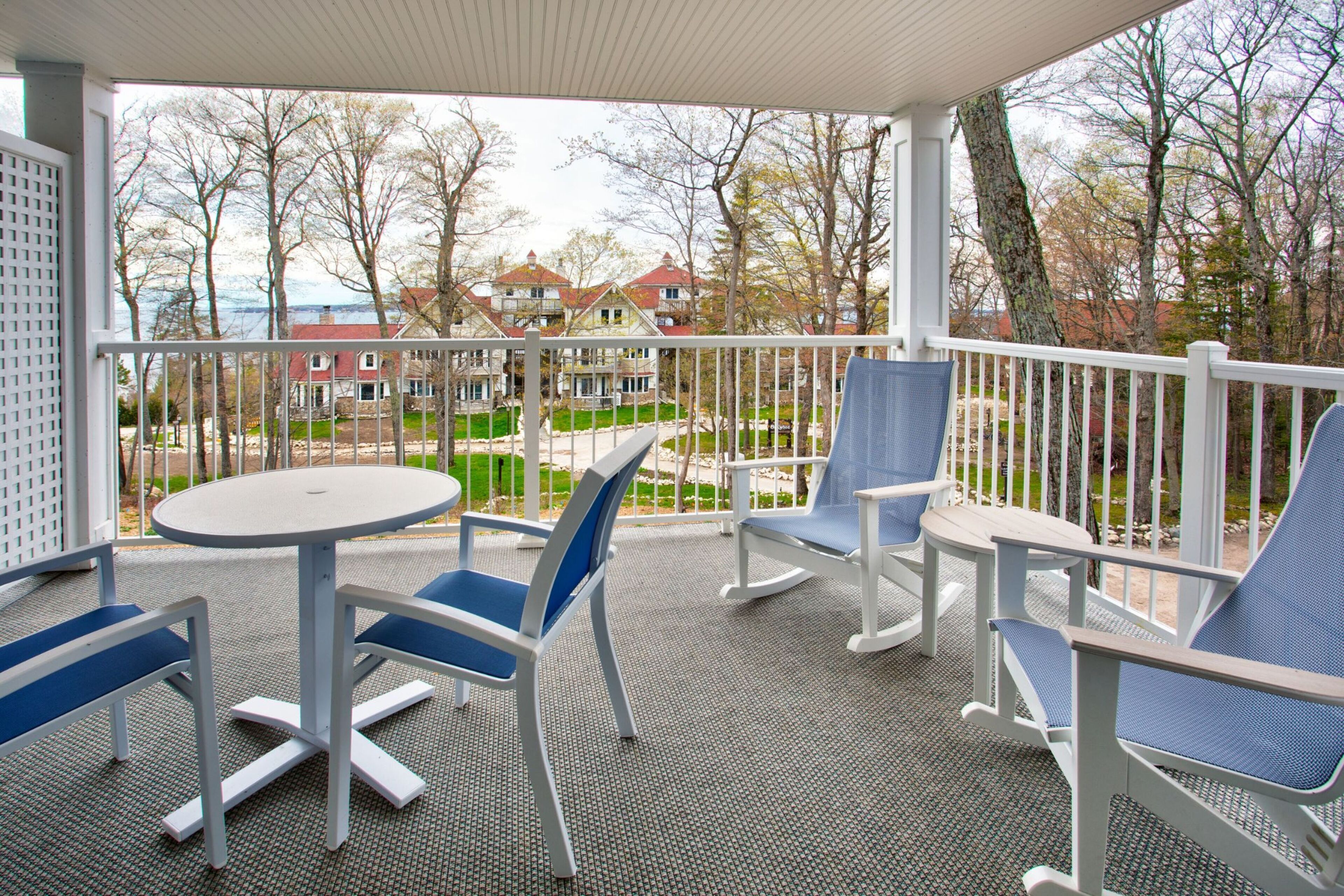 A covered outdoor seating area with a table and chairs, overlooking a residential neighborhood.