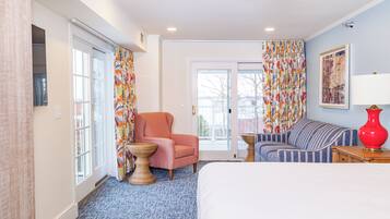 A hotel room with a bed, a chair, a sofa, a lamp, and a window with curtains.