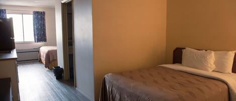 A hotel room with a large bed, a desk, and a window with curtains.