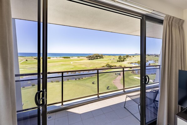 A balcony with a view of a golf course and a body of water.
