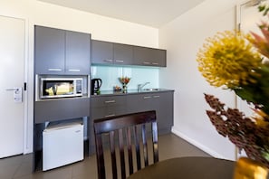 A modern kitchen with grey cabinets, a microwave, a small refrigerator, and a sink.