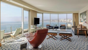 Amplio salón con un gran ventanal que ofrece vistas a la ciudad, un televisor de pantalla plana y asientos cómodos.