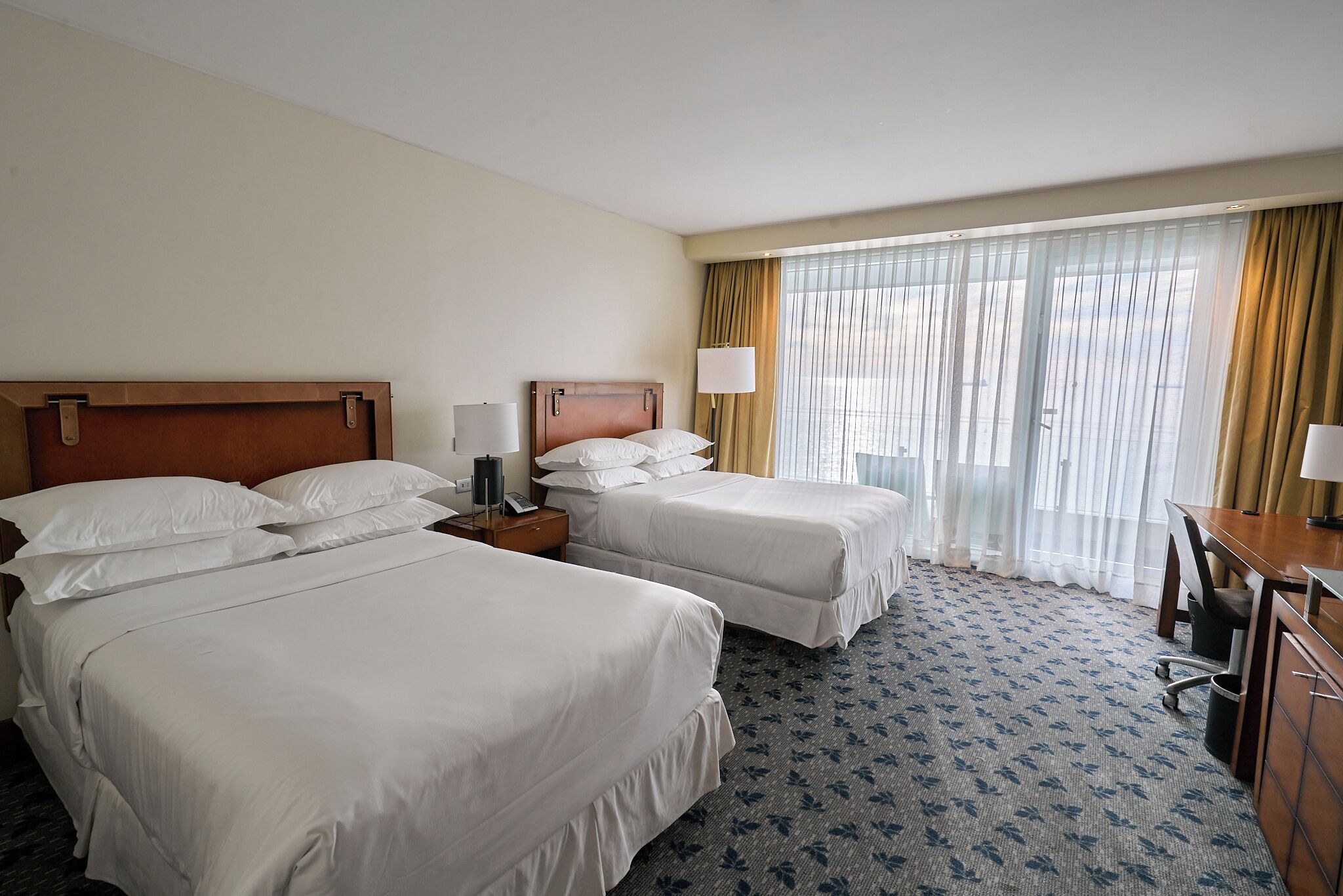 Une chambre d’hôtel avec deux lits, un bureau et une chaise.