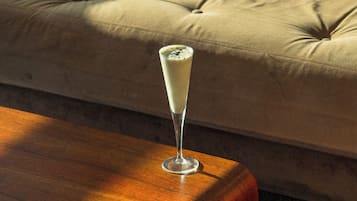 Um copo de bebida branca sobre uma mesa de madeira em um quarto com um sofá bege.
