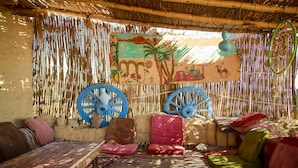 Una habitación con un muro tejido, un mural y una cama con cojines coloridos.