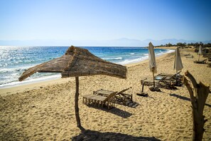 Aan een privéstrand, ligstoelen, parasols, strandlakens