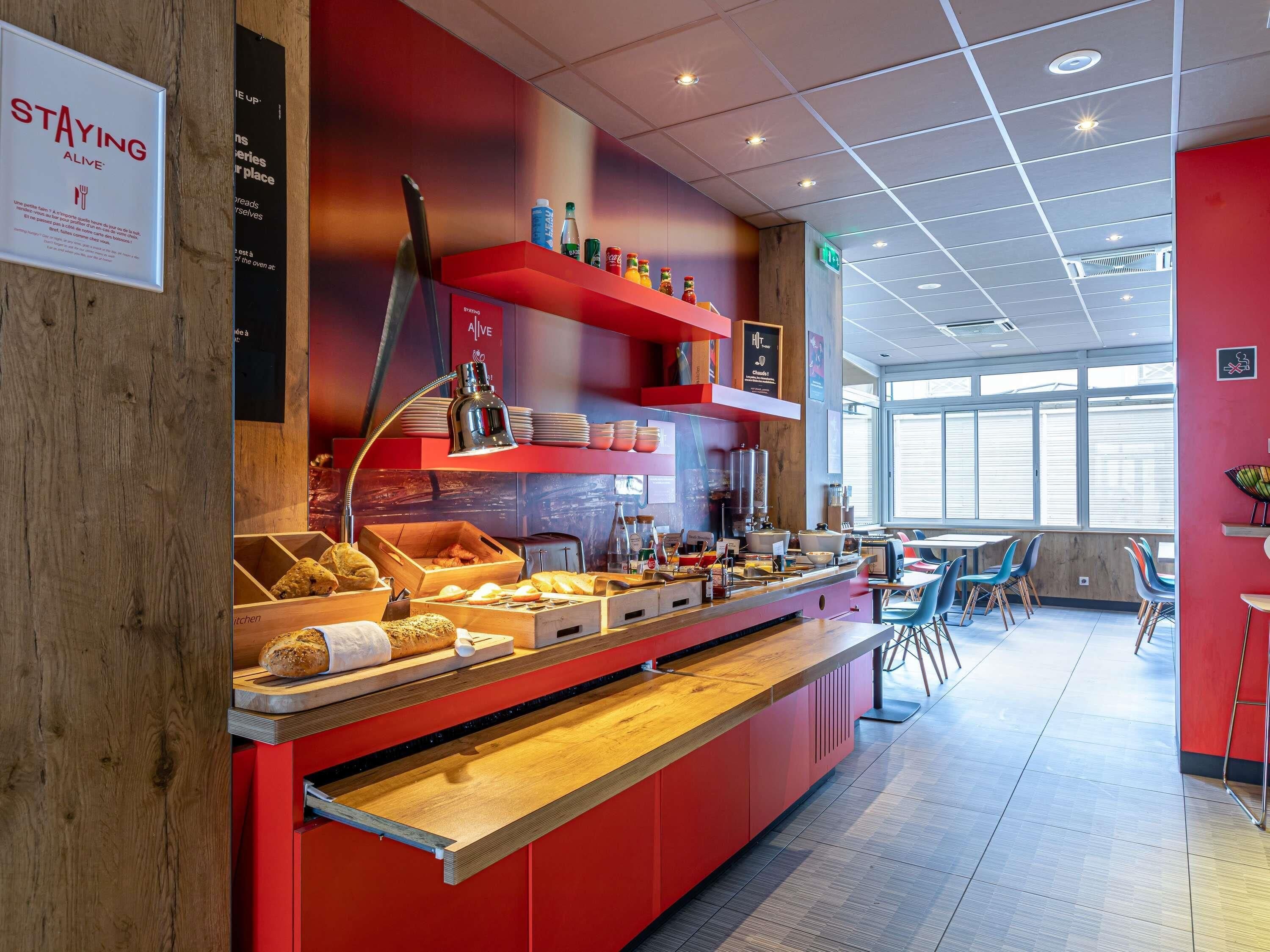 Una barra de desayuno moderna con decoración en tonos rojos, una variedad de alimentos y un interior limpio y bien iluminado.