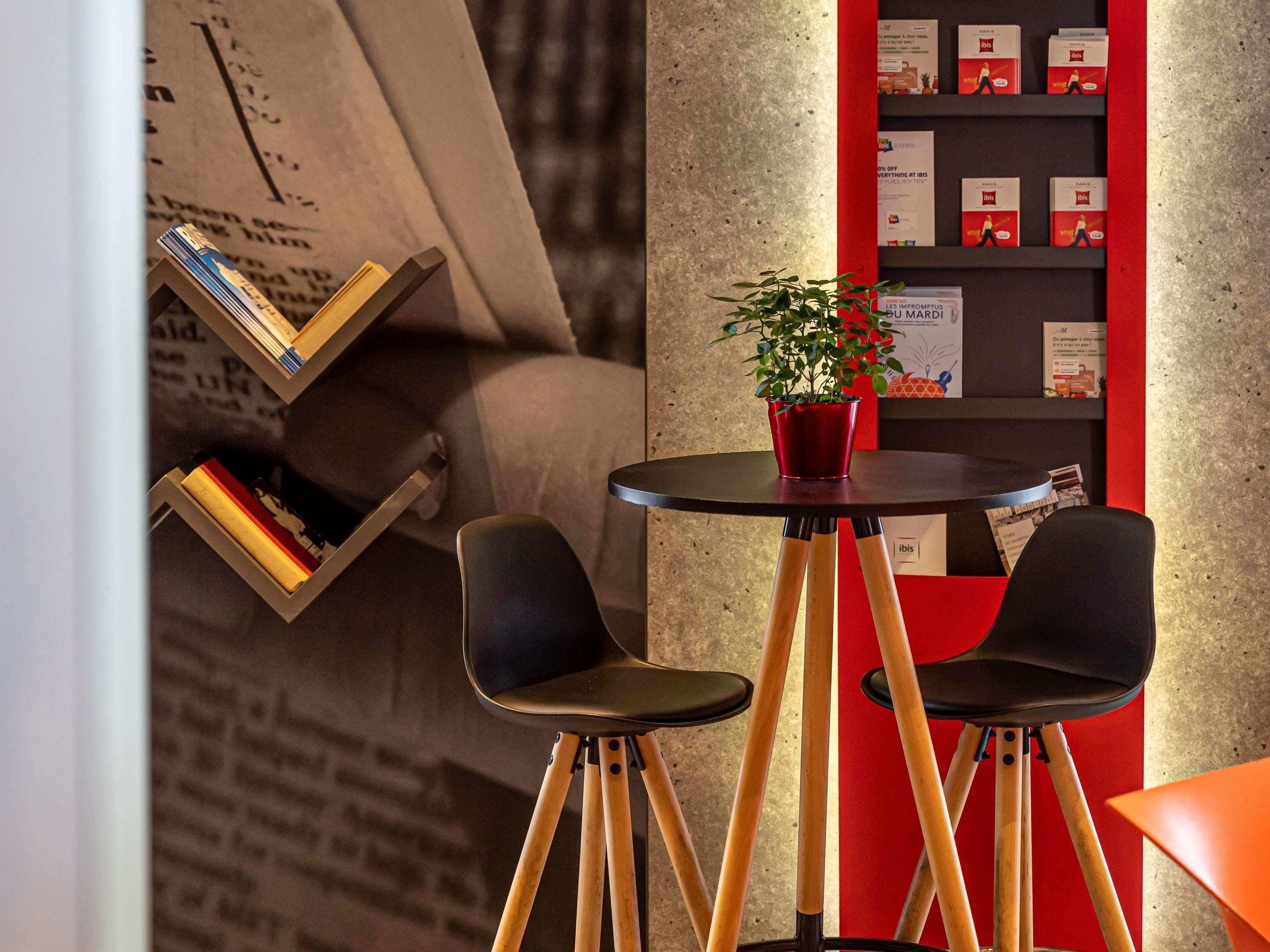 Ein modernes Interieur mit einem runden Tisch, zwei Stühlen, einer Bücherwand und einer roten Akzentwand.