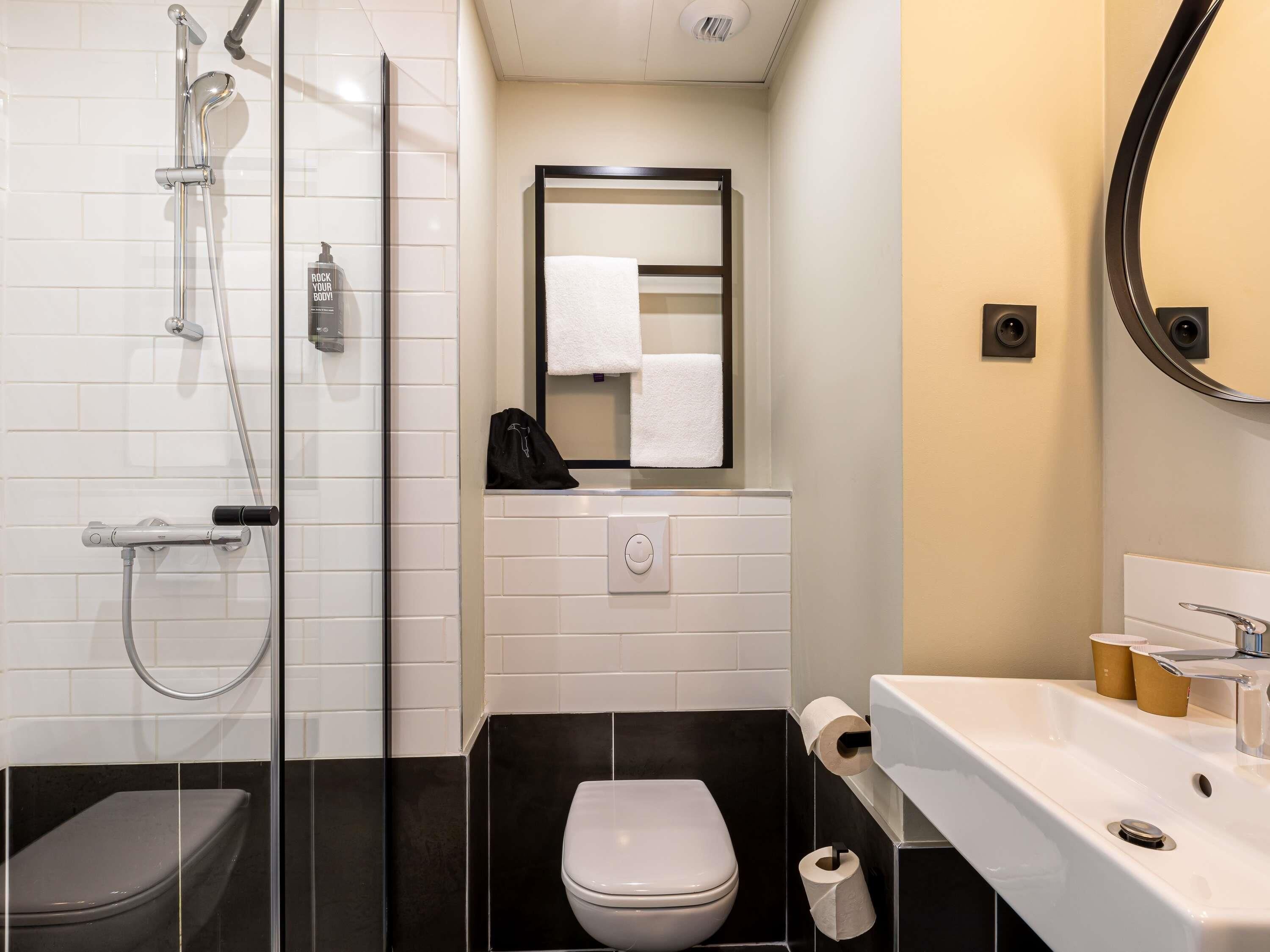A bathroom with a glass shower enclosure, a toilet, and a sink with a mirror.