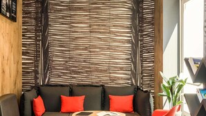 A modern living room with a sofa, a small round table, and a red chair. - ibis Paris Boulogne Billancourt (Boulogne-Billancourt)