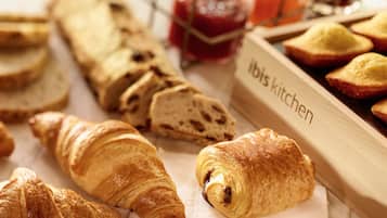 A variety of baked goods including croissants and bread, arranged on a wooden board labeled "ibis kitchen".