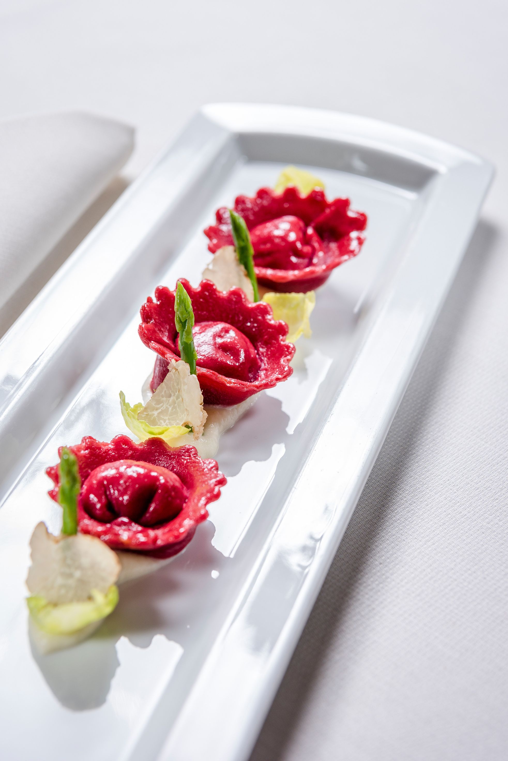 Une assiette rectangulaire blanche sur laquelle sont disposées en rangée cinq bouchées, rouges et vertes.