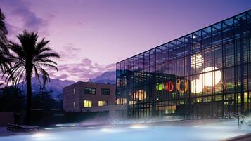 A modern building with large glass windows and a pool area.