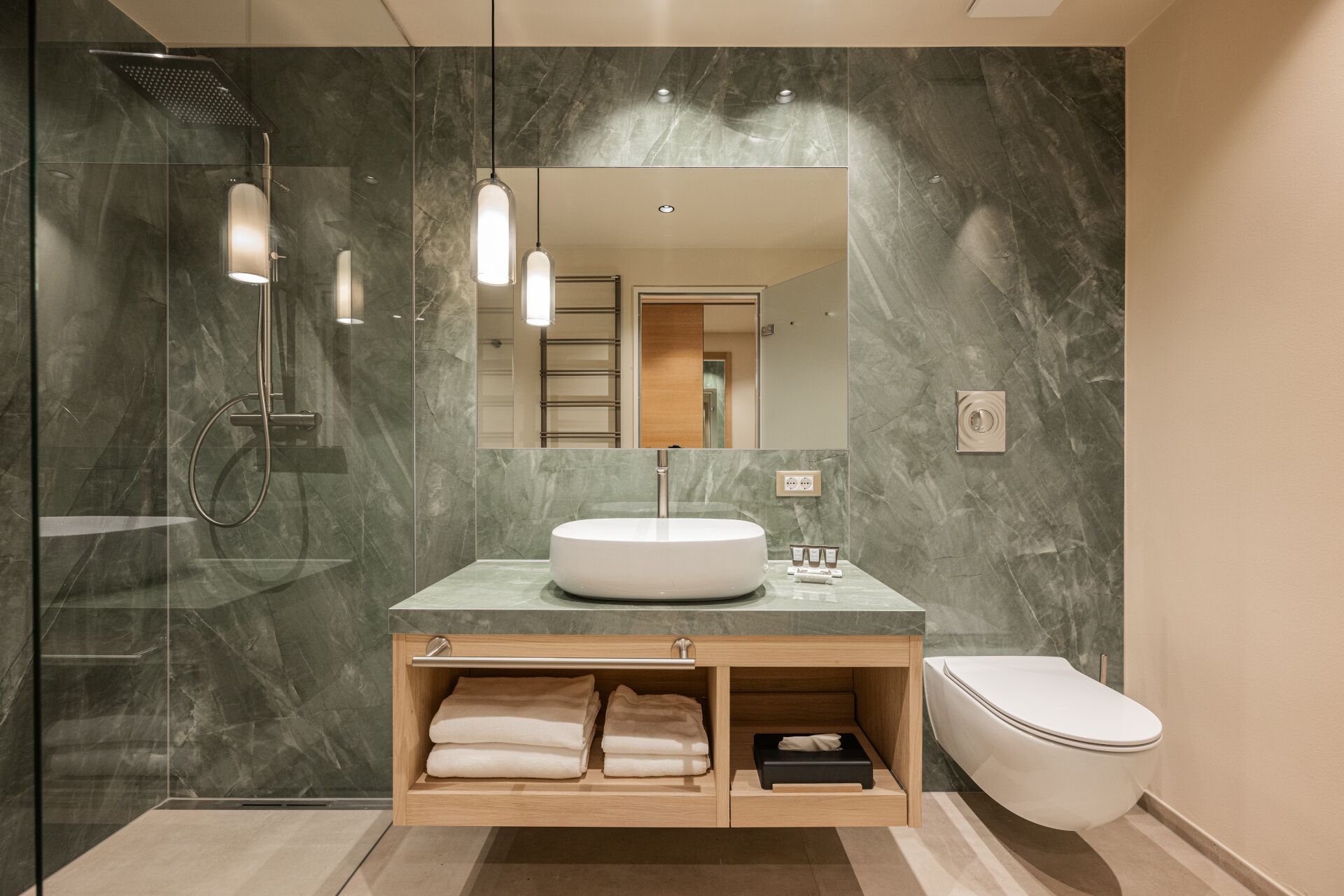 Un baño moderno con un espejo grande, un lavabo redondo, ducha y un inodoro.