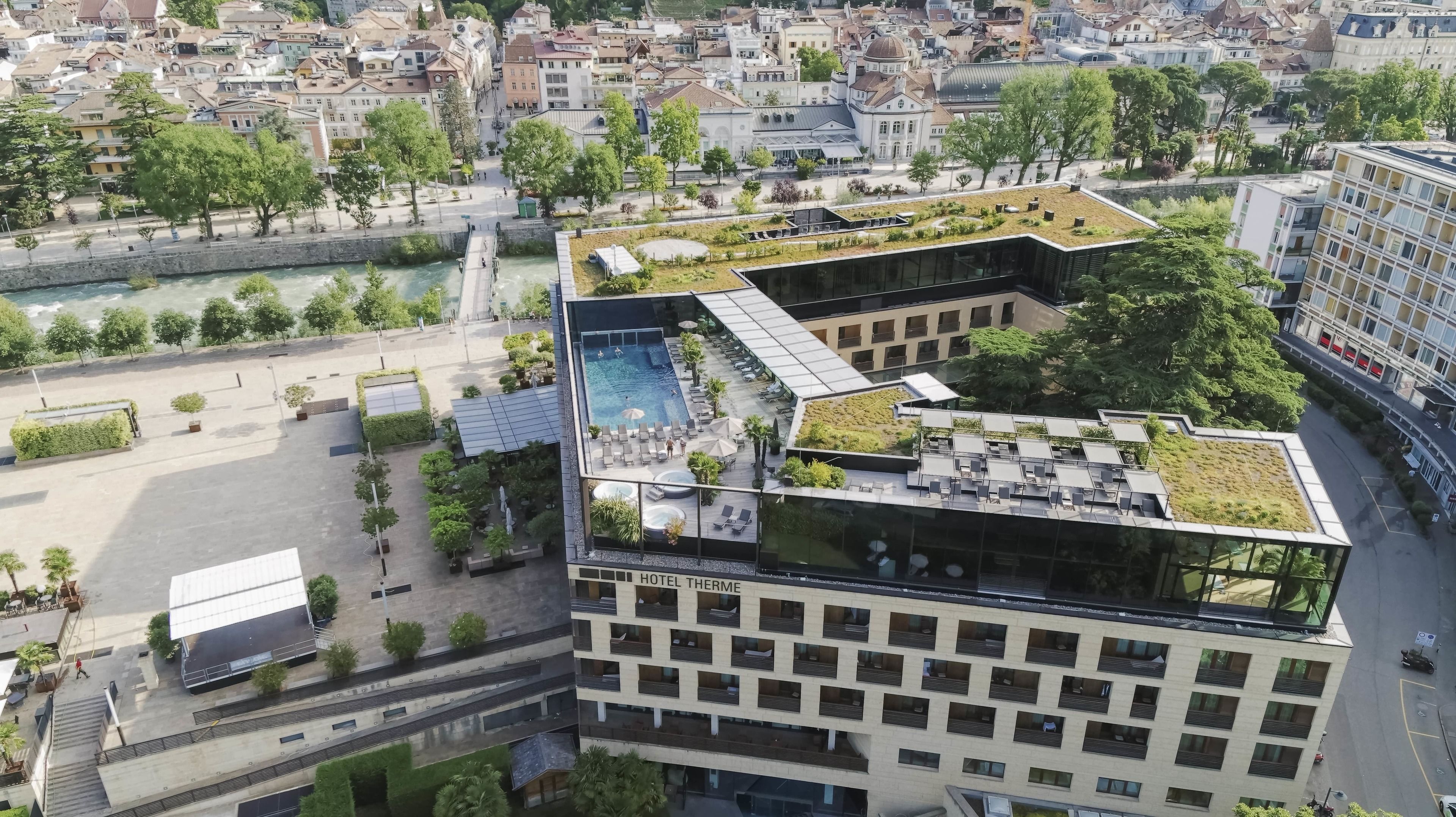 Un hotel moderno con piscina en la azotea, jardín en terrazas y vistas a la ciudad.