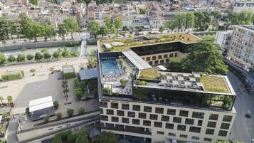 Un hotel moderno con piscina en la azotea, jardín en terrazas y vistas a la ciudad.