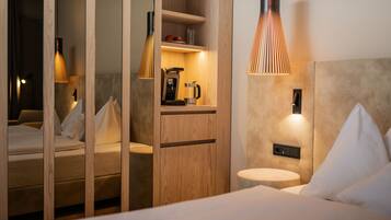 Een moderne hotelkamer met een bed, een bureau met een koffiezetapparaat en een spiegel.