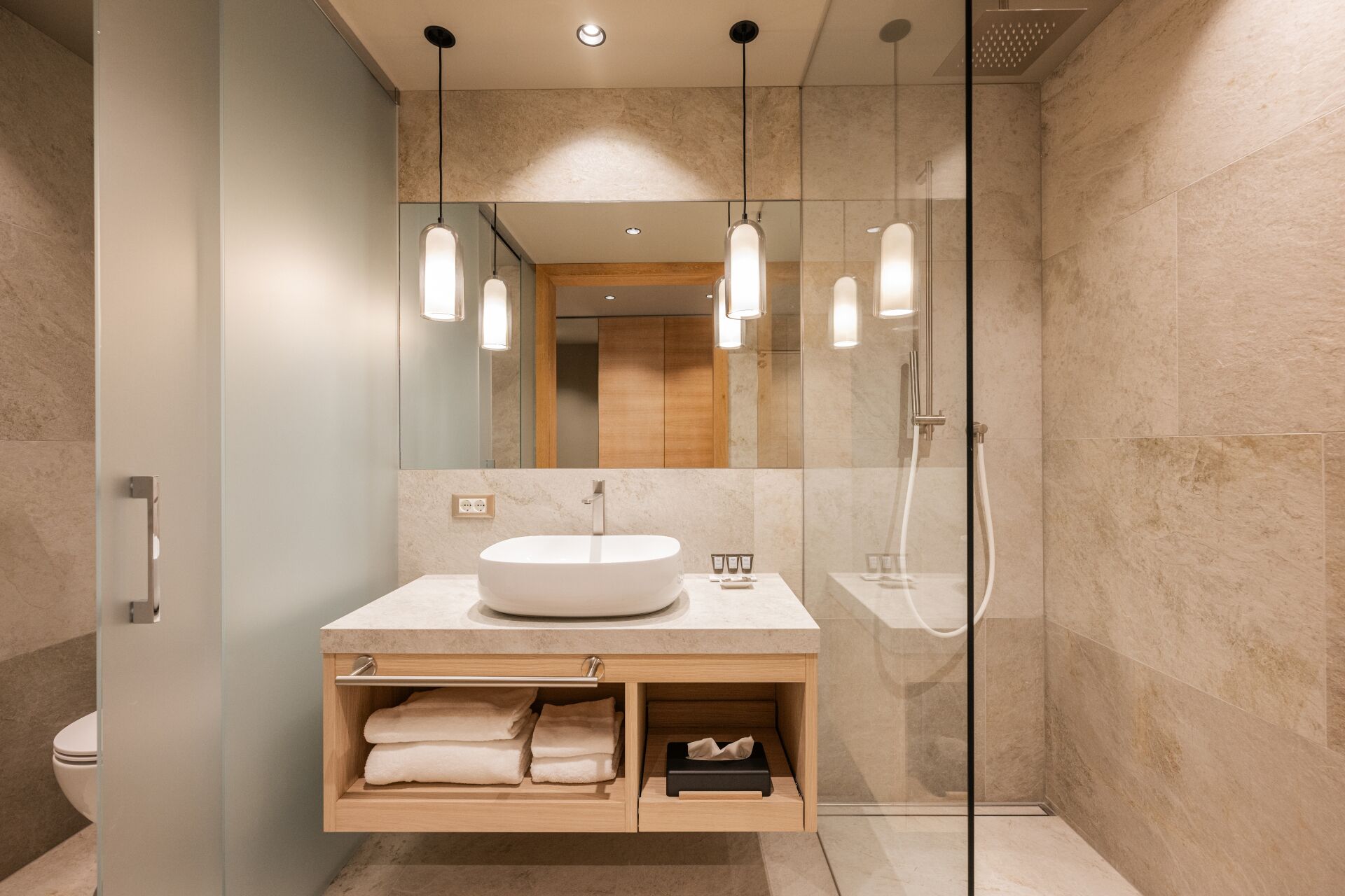 Un bagno moderno con un lavabo freestanding, cabina doccia in vetro e un grande specchio.