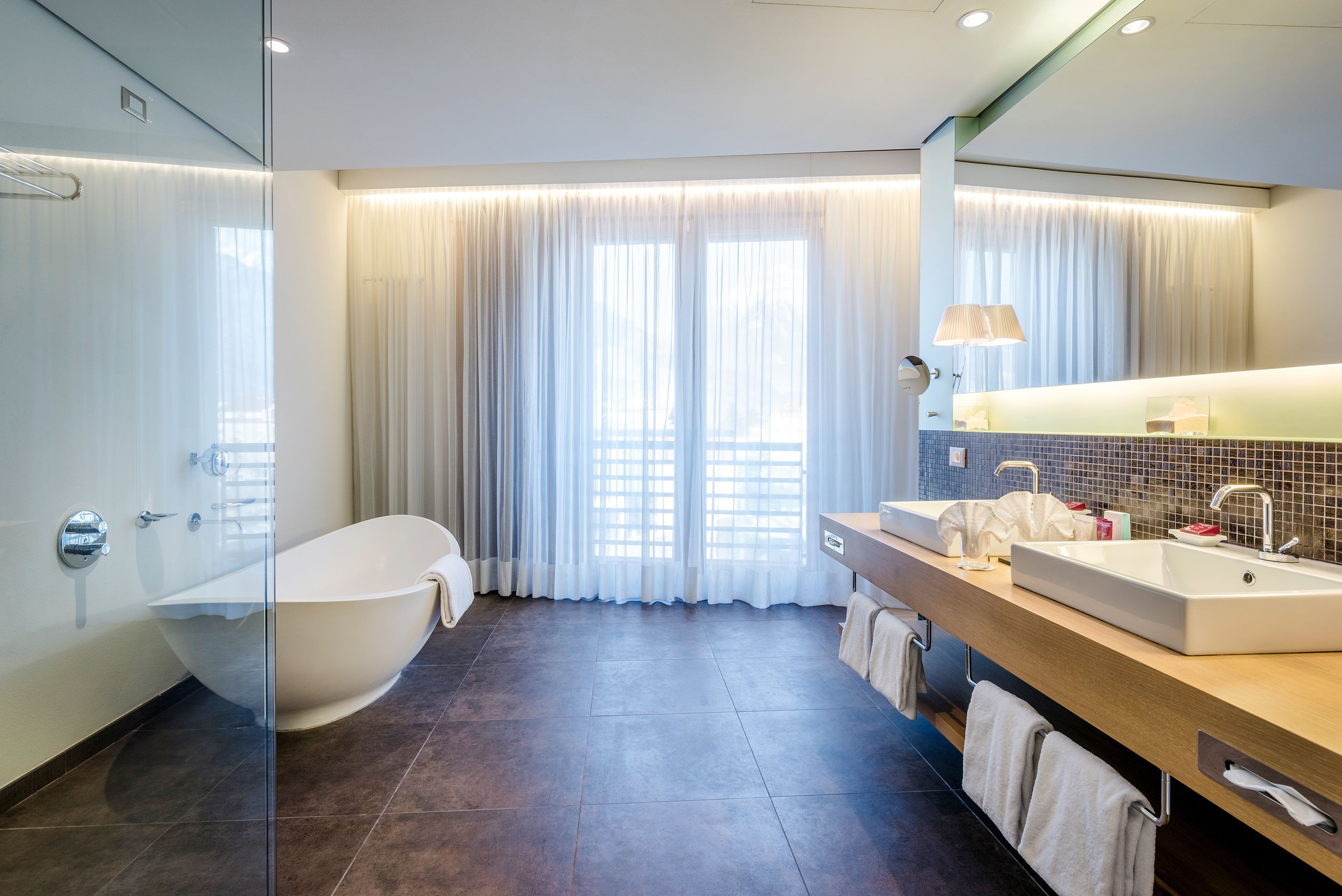 Une salle de bain moderne avec une baignoire sur pieds, un meuble-lavabo à deux vasques et un grand miroir.