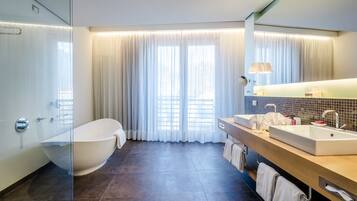 Une salle de bain moderne avec une baignoire sur pieds, un meuble-lavabo à deux vasques et un grand miroir.