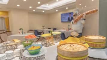 Montaje de buffet con diversos platos y una estatua de chef al fondo.