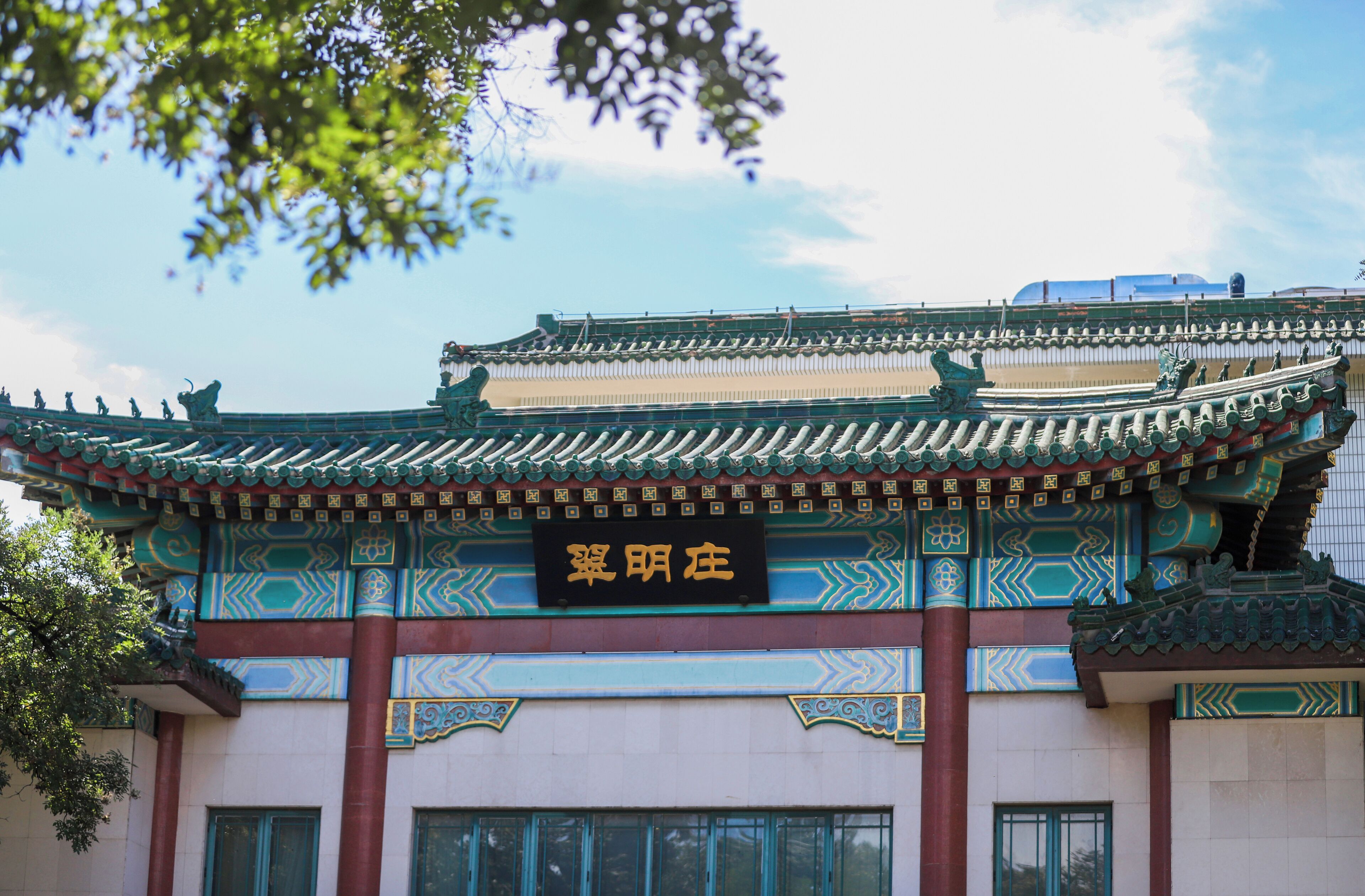 Un edificio tradicional con arquitectura ornamentada, un letrero con caracteres chinos y un cielo azul despejado.
