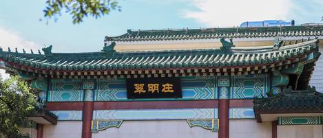 Un edificio tradicional con arquitectura ornamentada, un letrero con caracteres chinos y un cielo azul despejado.