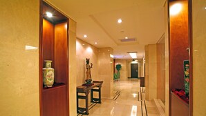 Un pasillo de hotel con paneles de madera, un banco y un florero en una estantería.