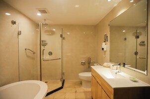 Ein modernes Badezimmer mit einer gläsernen Duschkabine, einer freistehenden Badewanne und einem Waschtisch mit großem Spiegel.
