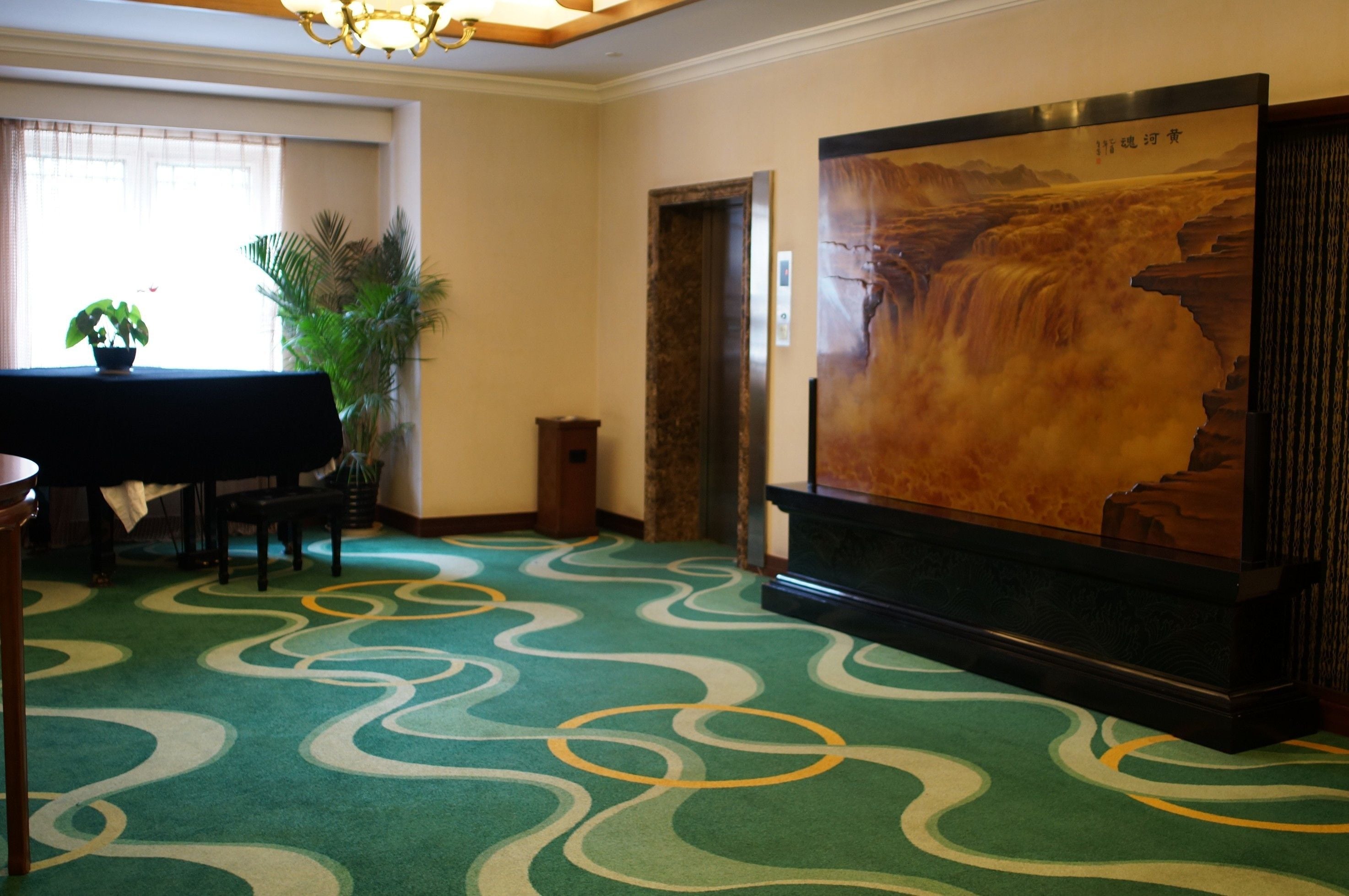 A room with a piano, a large painting of a waterfall, and a carpet with a wavy pattern.