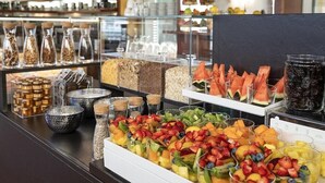 Mostrador de buffet con diferentes opciones de comida, incluyendo frutas, cereales y bebidas.