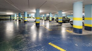 A multi-level underground parking garage with blue and yellow striped pillars, marked parking spaces, and several parked cars. - B&B HOTEL Imperia Rossini al Teatro (Imperia)