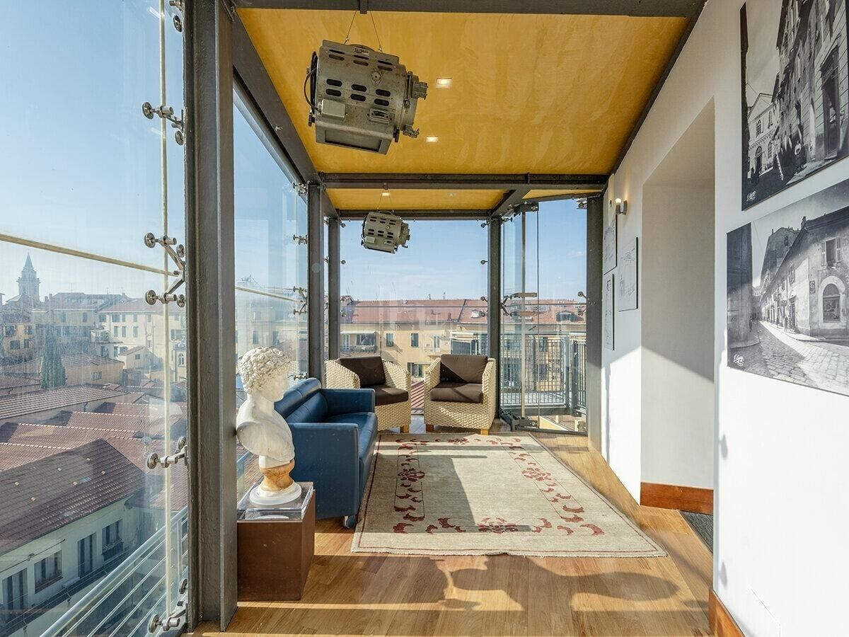 Eine hohe Apartmentwohnung mit einem Balkon, ausgestattet mit einer Couch, Sesseln und einer Statue.