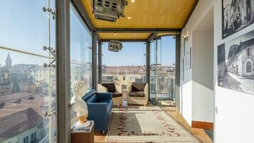 Eine hohe Apartmentwohnung mit einem Balkon, ausgestattet mit einer Couch, Sesseln und einer Statue.