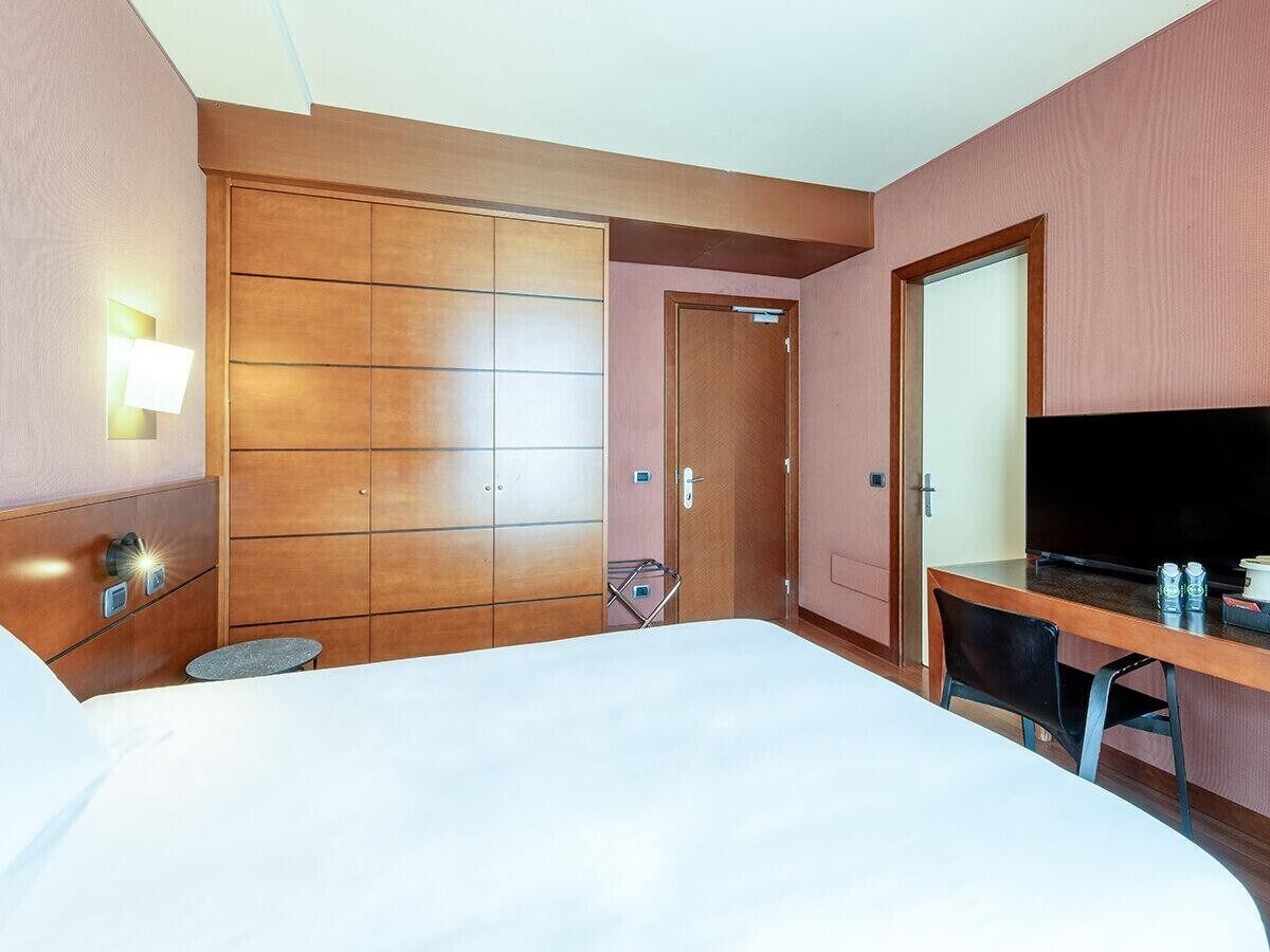 Een hotelkamer met een bed, een bureau, een televisie en een kledingkast.
