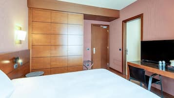 Een hotelkamer met een bed, een bureau, een televisie en een kledingkast.