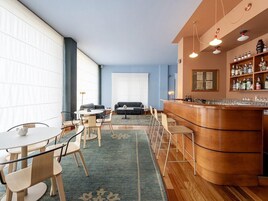 A hotel room with a bar area, seating arrangement, and a large window.