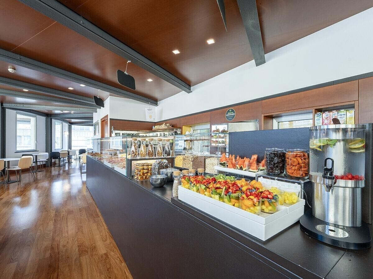 Eine moderne Cafeteria mit einer langen Theke, verschiedenen Essensausgaben und Sitzbereichen.