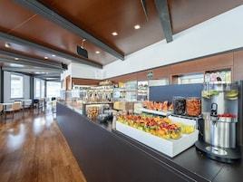 Eine moderne Cafeteria mit einer langen Theke, verschiedenen Essensausgaben und Sitzbereichen.
