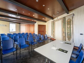 A conference room with a long table and blue chairs, a projector, and a large window.