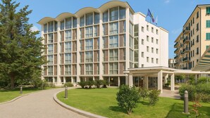 A multi-story hotel with a curved facade, large windows, and a covered entrance area. - B&B HOTEL Imperia Rossini al Teatro (Imperia)