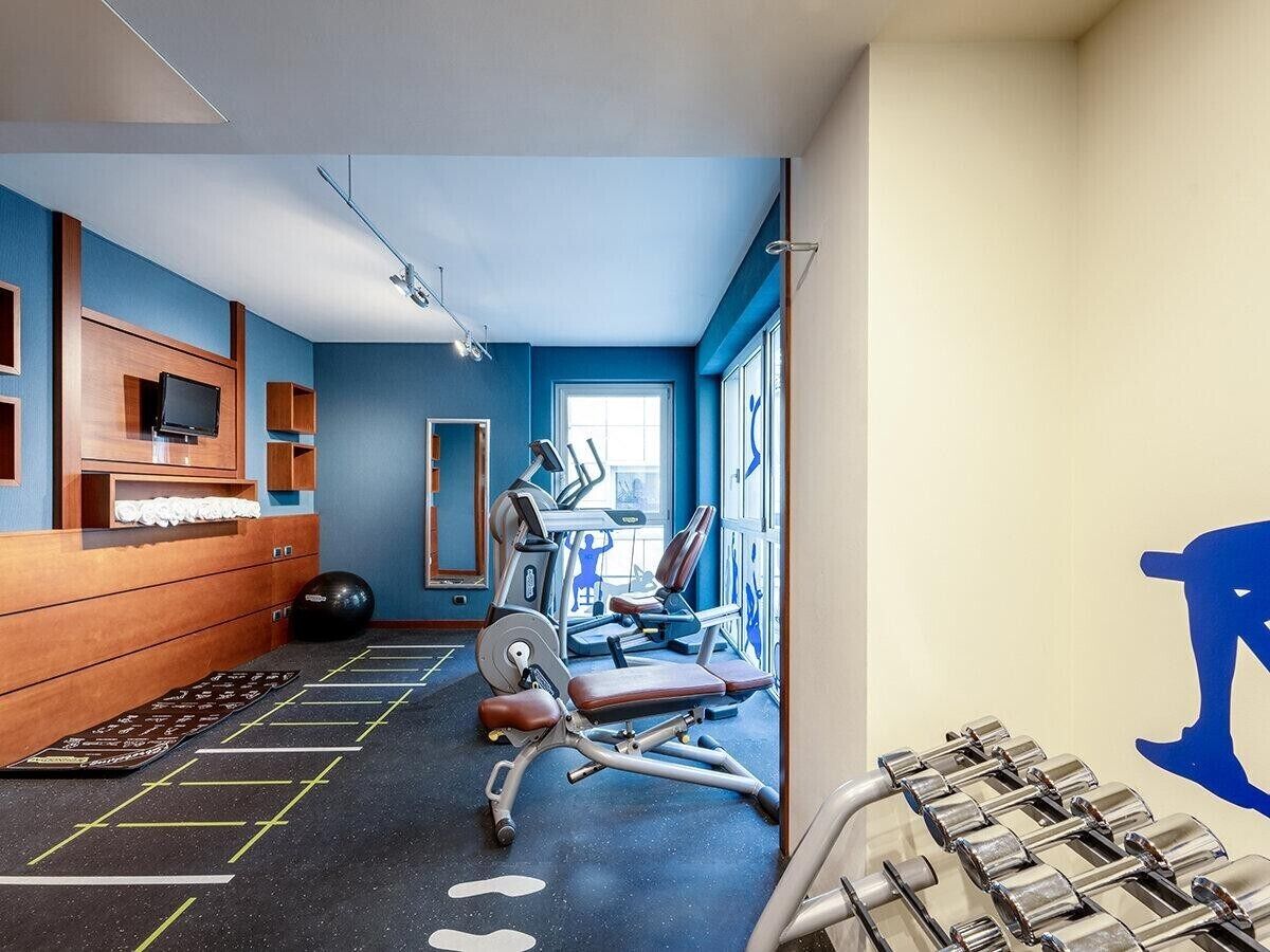 A gym with exercise equipment, a mirrored wall, and a blue wall.
