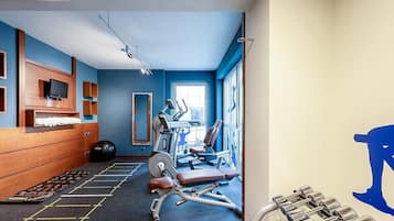 A gym with exercise equipment, a mirrored wall, and a blue wall.