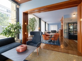 Un interior moderno con un sofá, una mesa con un adorno, una zona de comedor con sillas y una barra con un refrigerador.