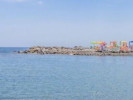 Una costa rocosa con una fila de sombrillas y sillas de playa coloridas.