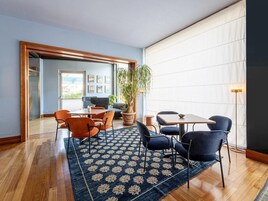 A modern interior with a dining area, a large potted plant, and a view through an open door.