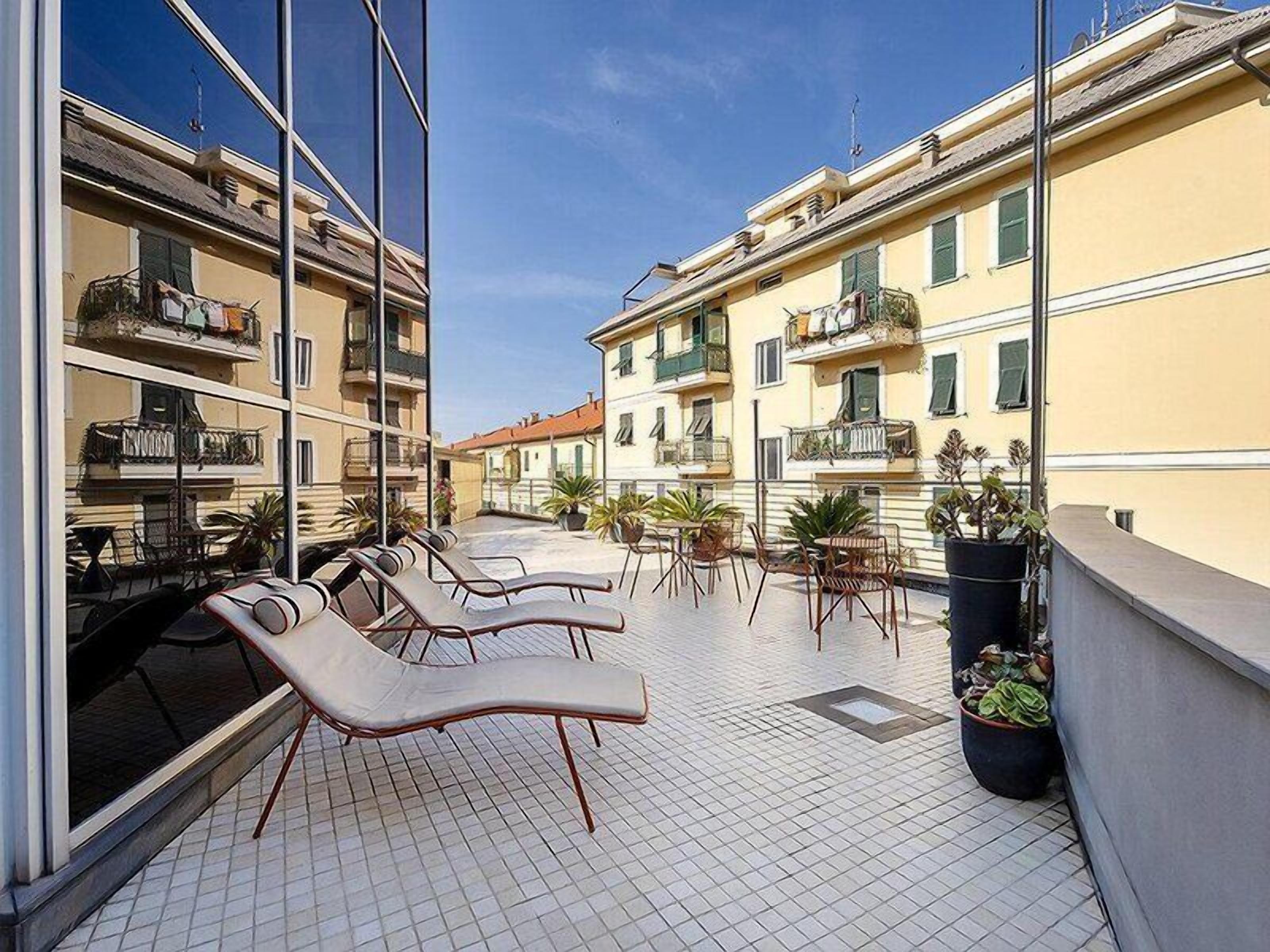A balcony with sun loungers and potted plants.