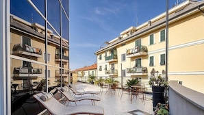 A balcony with sun loungers and potted plants. - B&B HOTEL Imperia Rossini al Teatro (Imperia)